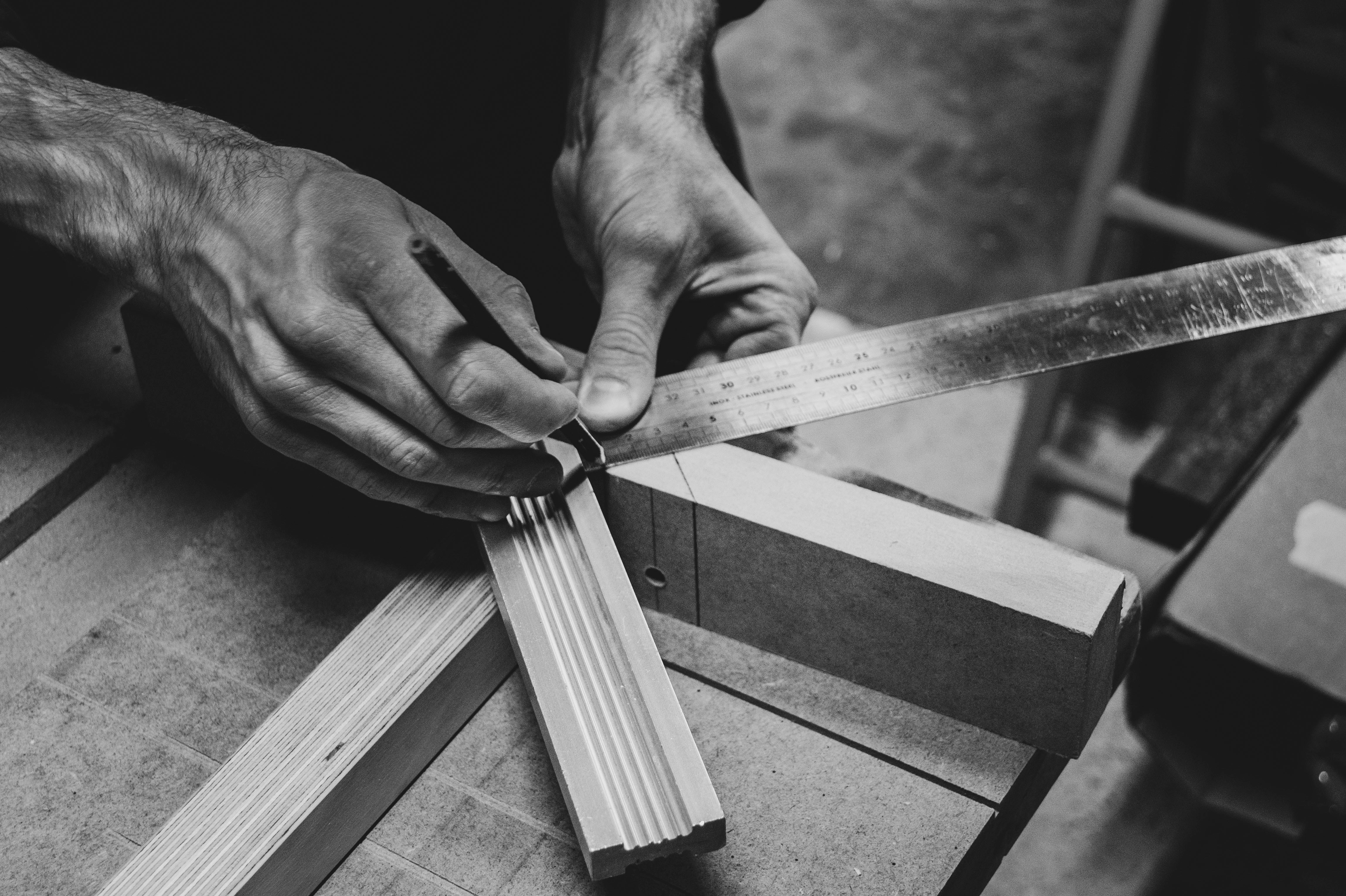 Hands measuring and marking wood in a workshop
