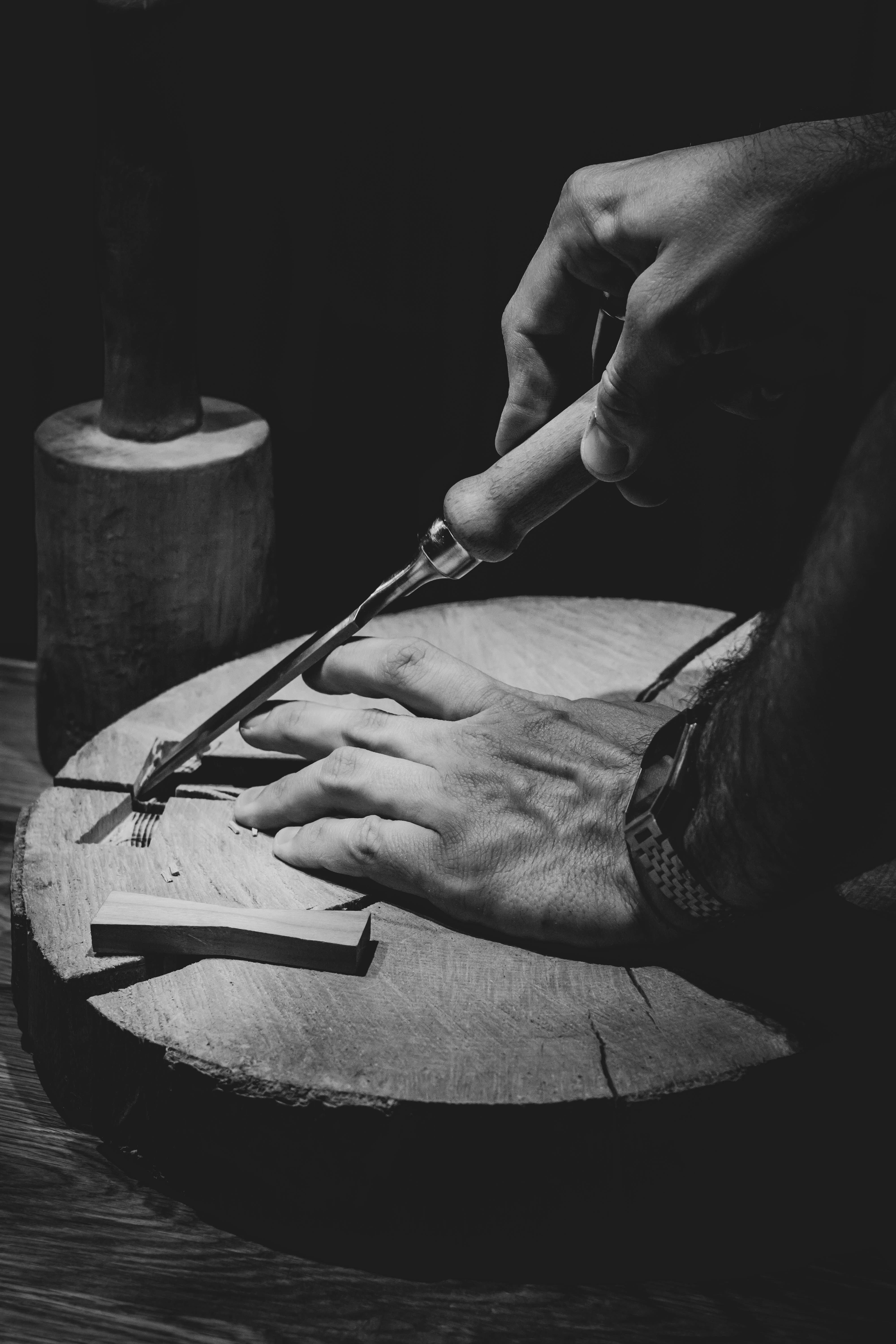 Hands carving wood with a hand tool